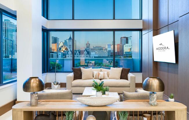 A light-filled resident lounge at Modera McGavock, where expansive windows and refined design create a comfortable place to relax and connect.