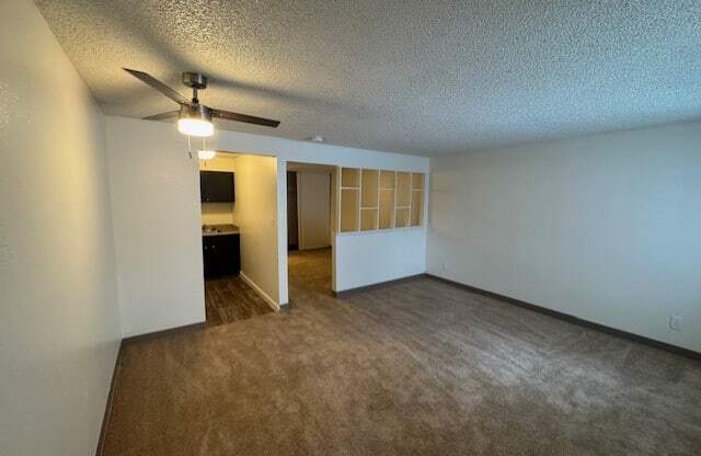 A room with a ceiling fan and carpeted floor.