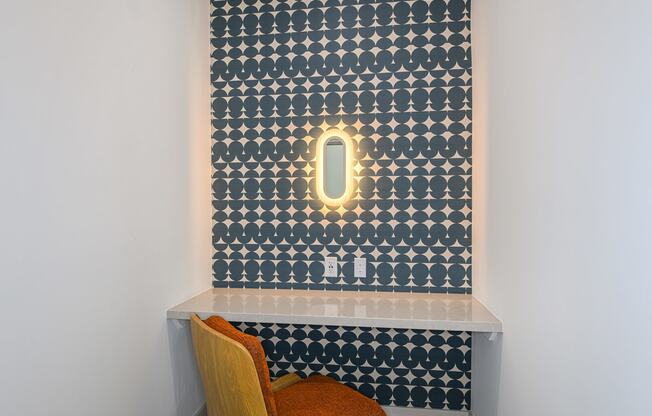 a small desk with a chair in front of a wall with a patterned wallpaper and a
