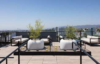 A rooftop patio with white bean bag chairs and a black railing at Skylar At Sunset Apartments, Los Angeles, CA