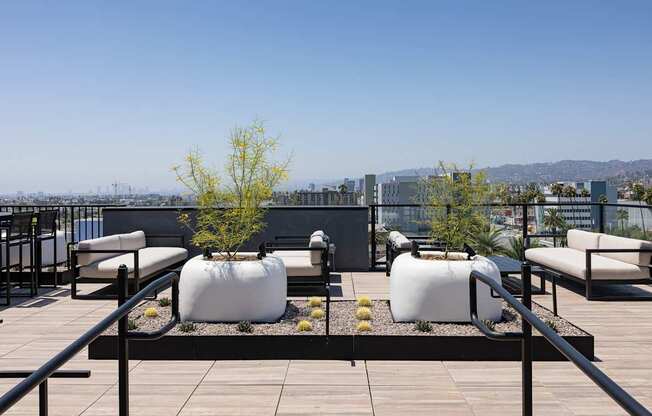 A rooftop patio with white bean bag chairs and a black railing at Skylar At Sunset Apartments, Los Angeles, CA