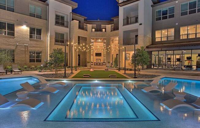 a swimming pool with chairs in front of an apartment building at Hunters Creek Apartments, Texas