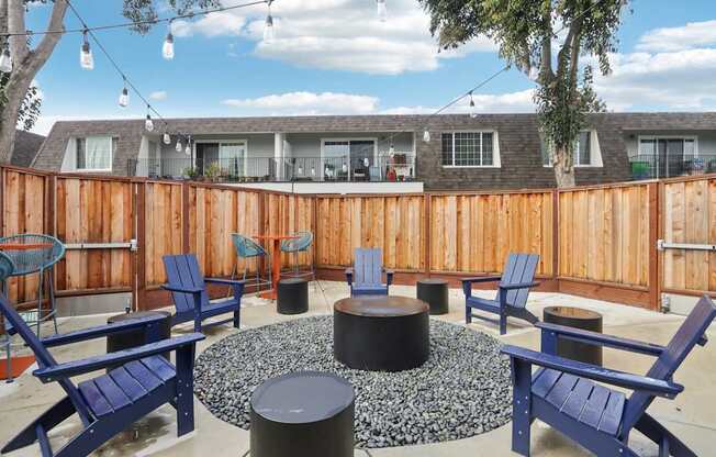 A patio with blue chairs and a fire pit.