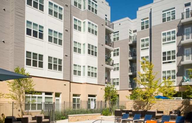 an outdoor patio with tables and chairs in front of an apartment building