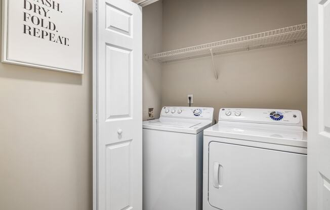 an empty laundry room with two white washers and dryers and a white door