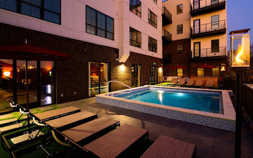 a pool with lounge chairs and umbrellas in front of an apartment building at Fairfax, Grandview, 43212
