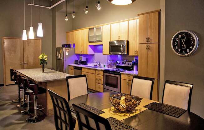 A kitchen with a table and chairs in the foreground and a clock on the wall.