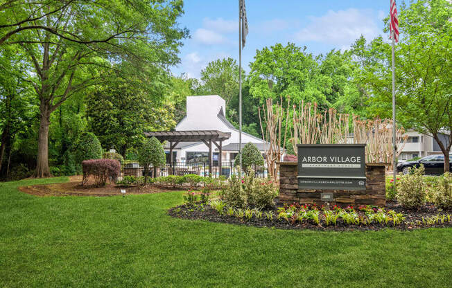 a view of the arbor village sign with a tent and trees in the background