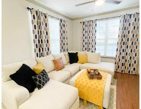 a living room with a white couch and a yellow ottoman