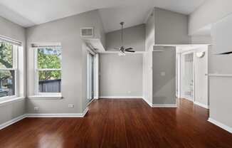 an empty living room with wood floors and a ceiling fan