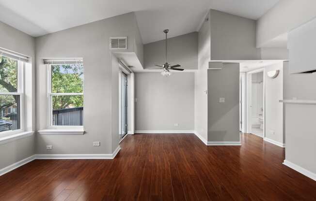 an empty living room with wood floors and a ceiling fan