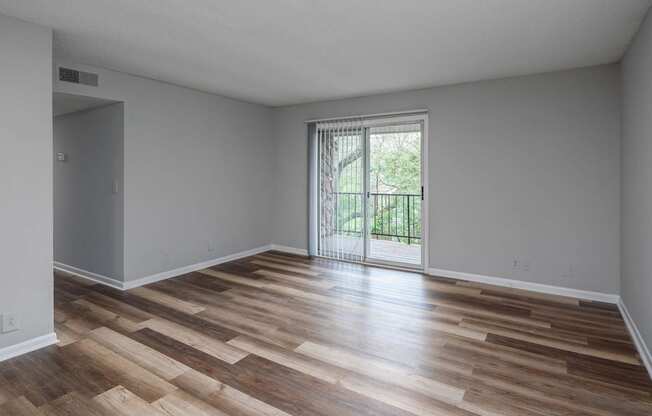 a bedroom with hardwood floors and a sliding glass door to a balcony