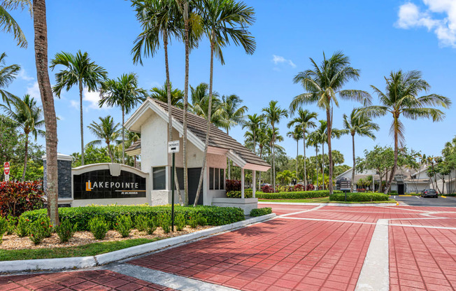 a building with palm trees in front of it and a red sidewalk