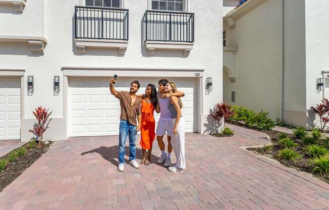 Three people taking a selfie in front of a white building.