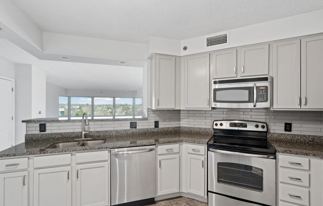 a kitchen with white cabinets and appliances and granite counter tops