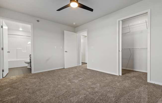 A room with a ceiling fan and carpeted floor.