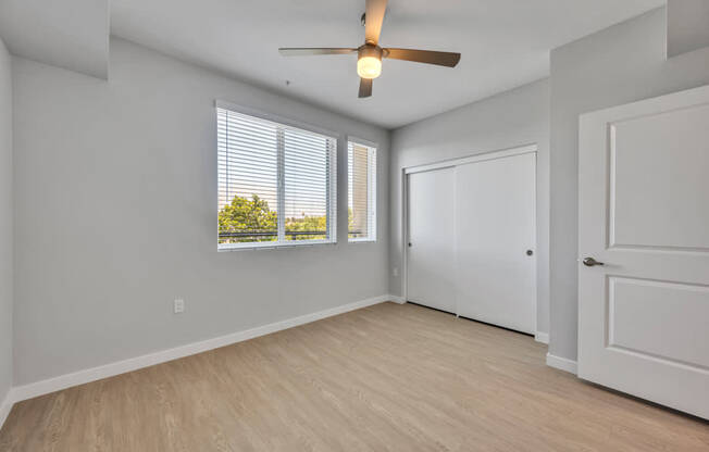 A room with a ceiling fan and a window with blinds.