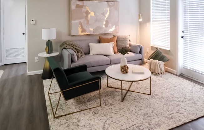 The Addison at Southfield apartment living space furnished with a gray couch and velvet side chair