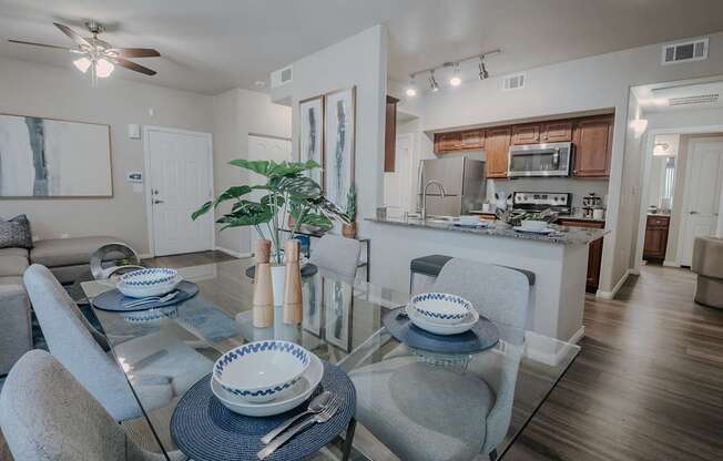 A modern dining room with a glass table and grey chairs.