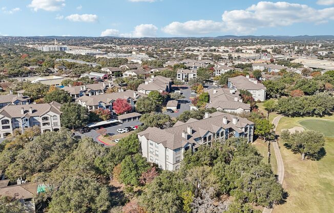 A bird's eye view of a residential area with houses and a golf course.