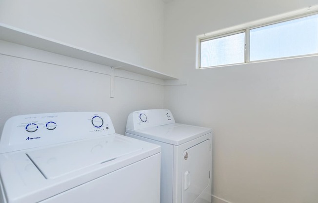 Two white front loading washing machines in a laundry room.