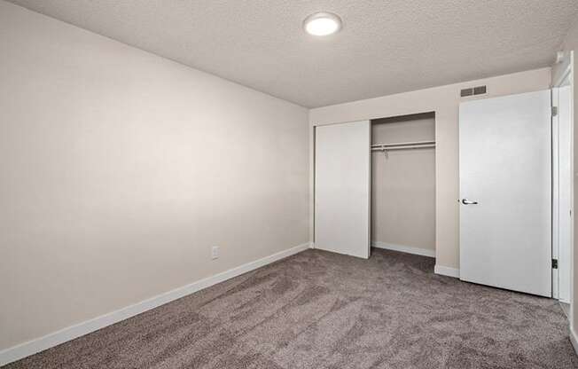 a bedroom with a carpeted floor and a door to a closet