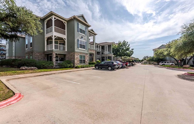 A parking lot in front of a multi-story apartment building.