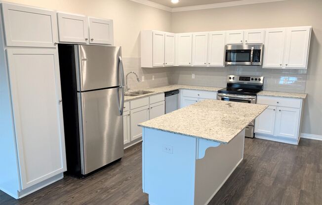 B2 (2-car) Kitchen with island, granite countertops, stainless steel appliances, white cabinets
