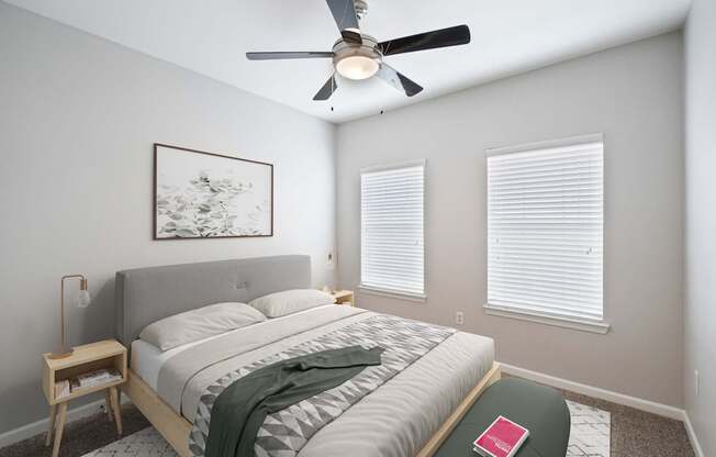 A bedroom with a bed, a ceiling fan, and a picture on the wall.