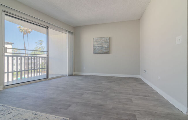 an empty living room with a sliding glass door to a balcony at Citra Apartments LLC, California, 92107