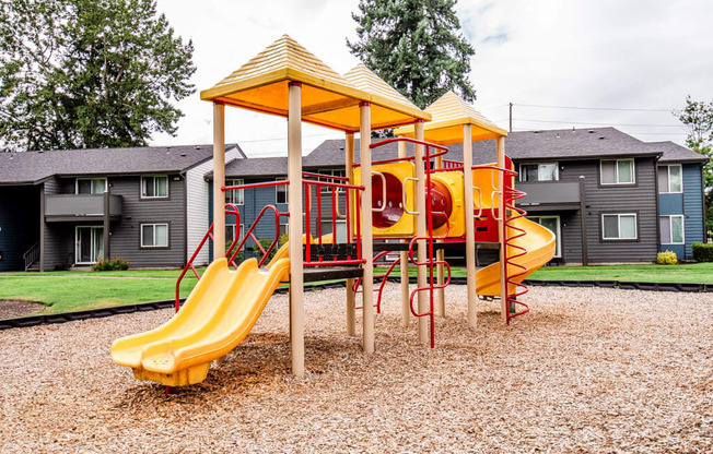 A playground with a yellow slide and a red and yellow structure.