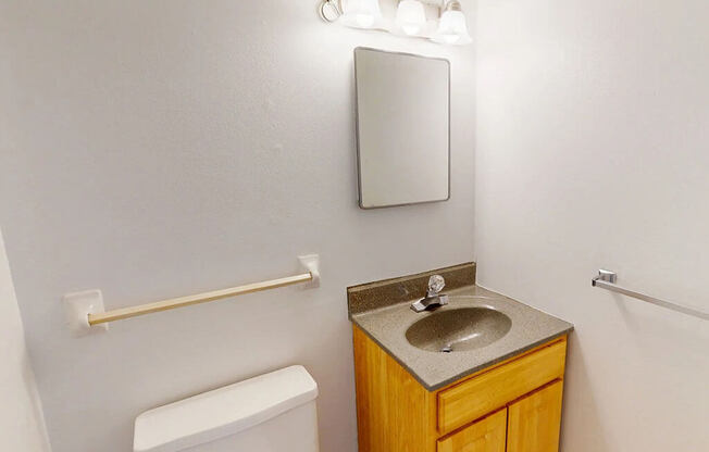 A bathroom with a toilet, sink and mirror.