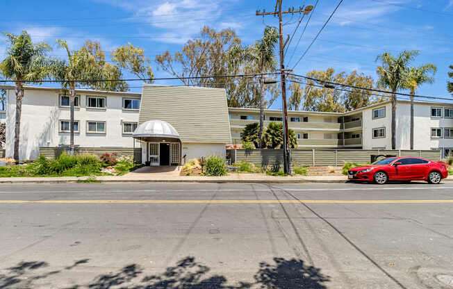 A red car is parked on the street in front of a building.