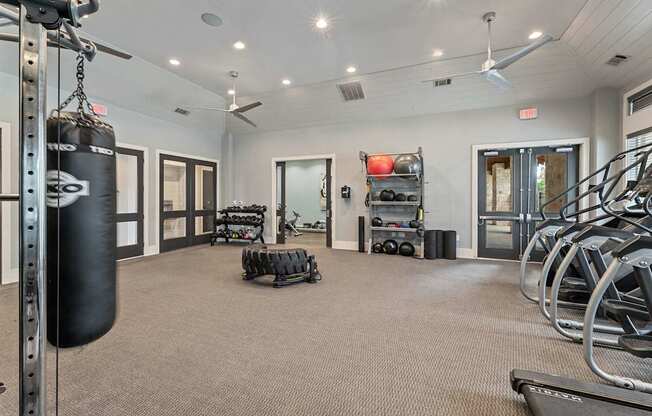 A gym with a punching bag, treadmills, and other exercise equipment.