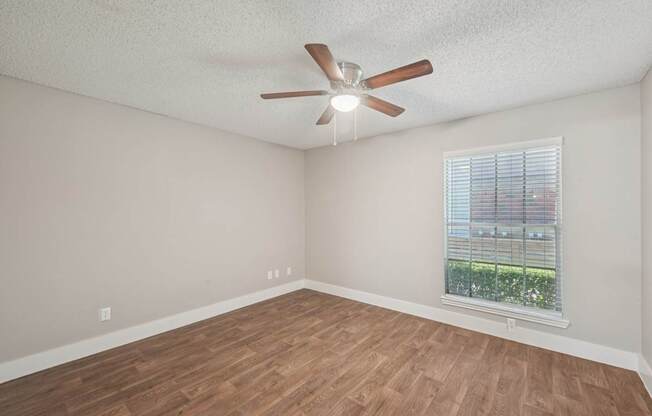 Empty room with a ceiling fan and a window.