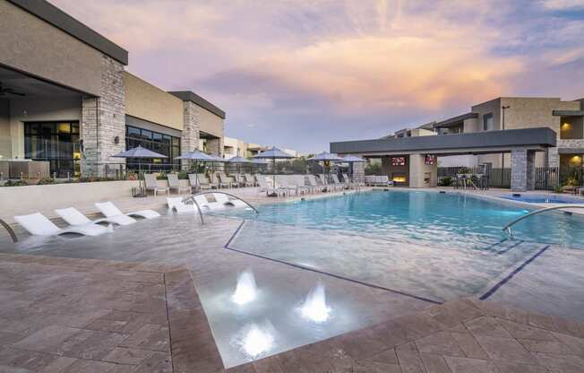 a swimming pool with chaise lounge chairs and umbrellas in front of a hotel