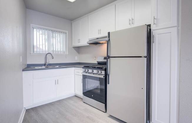 A kitchen with white cabinets and a white refrigerator.