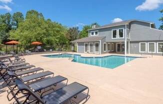 a pool with lounge chairs and a house in the background