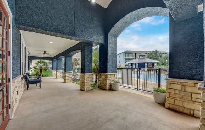 A patio area with a pool and a building in the background.