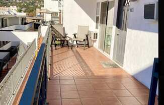 A balcony with a table and chairs overlooking a town.