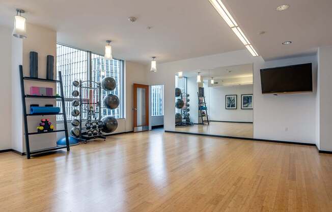 A gym with a mirror, weights, and exercise equipment.
