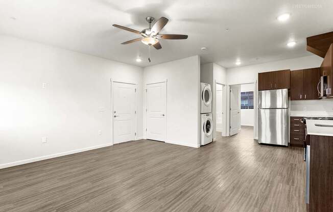 A spacious kitchen and living room with wood flooring and white walls.