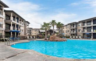 a large swimming pool with an apartment building in the background at Legacy Flats, San Antonio, TX