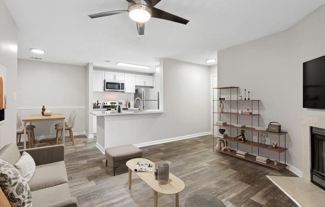 Model Living Room With Wood-Style Flooring, a Fireplace and Kitchen View at Element 41 Apartments in Marietta, GA.