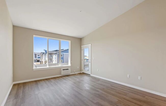 an empty living room with a large window and wooden floors