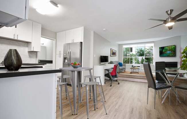 Dining area with ceiling fan, cozy fireplace in the den and living room, wood-like floors throughout