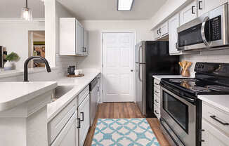 A kitchen with black appliances and white cabinets.