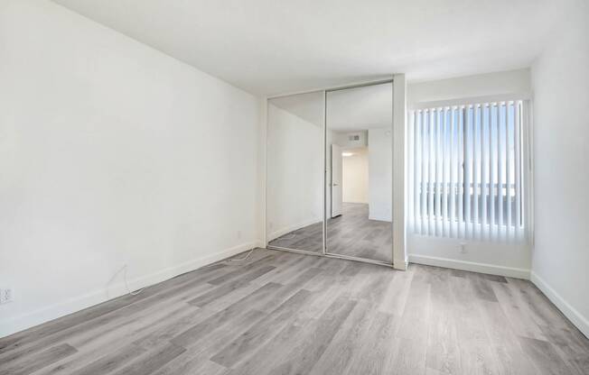 an empty living room with a mirror and a sliding glass door