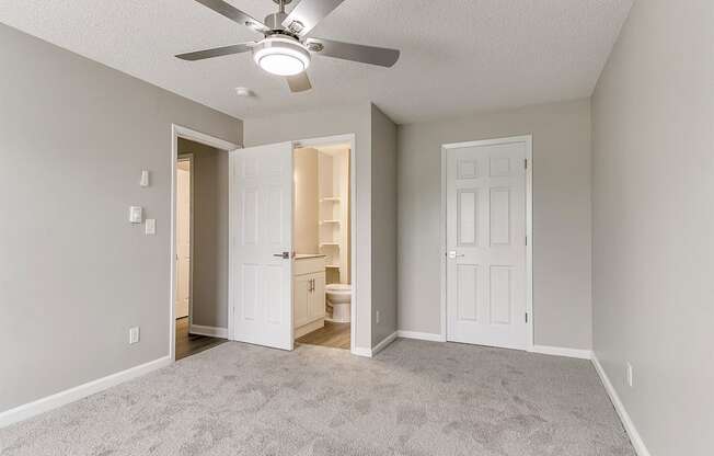 an empty living room with a ceiling fan and a closet