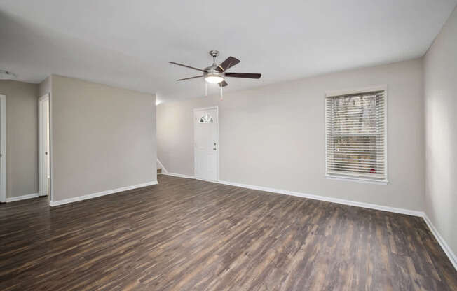 A room with a ceiling fan and wooden flooring.